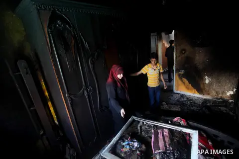Palestinians inspect the damage in the bedroom of one-year-old Fathi Baghdadi, who died after a fire from a candle that swept through their home in the Bureij refugee camp in the center of the Gaza Strip on September 26,...