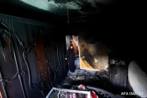Palestinians inspect the damage in the bedroom of one-year-old Fathi Baghdadi, who died after a fire from a candle that swept through their home in the Bureij refugee camp in the center of the Gaza Strip on September 26,...