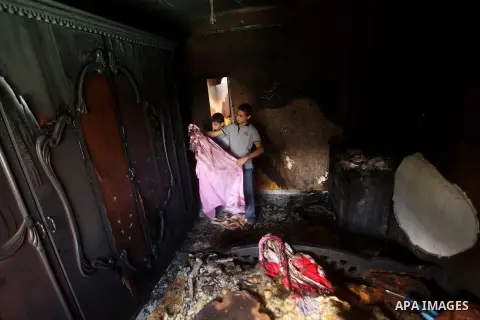 Palestinians inspect the damage in the bedroom of one-year-old Fathi Baghdadi, who died after a fire from a candle that swept through their home in the Bureij refugee camp in the center of the Gaza Strip on September 26,...