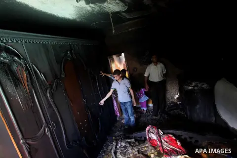 Palestinians inspect the damage in the bedroom of one-year-old Fathi Baghdadi, who died after a fire from a candle that swept through their home in the Bureij refugee camp in the center of the Gaza Strip on September 26,...