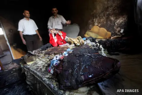 Palestinians inspect the damage in the bedroom of one-year-old Fathi Baghdadi, who died after a fire from a candle that swept through their home in the Bureij refugee camp in the center of the Gaza Strip on September 26,...