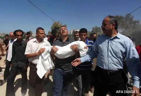 Palestinian mourners carry the body of three-year-old Fathi Baghdadi, who was killed in an overnight domestic fire, lies on a couch at his home in the Bureij refugee camp, centeral Gaza Strip, on September 26, 2012. The...