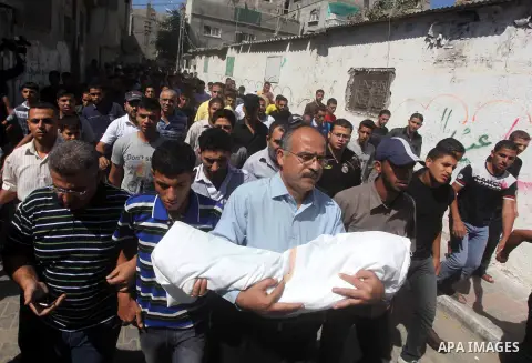 Palestinian mourners carry the body of three-year-old Fathi Baghdadi, who was killed in an overnight domestic fire, lies on a couch at his home in the Bureij refugee camp, centeral Gaza Strip, on September 26, 2012. The...
