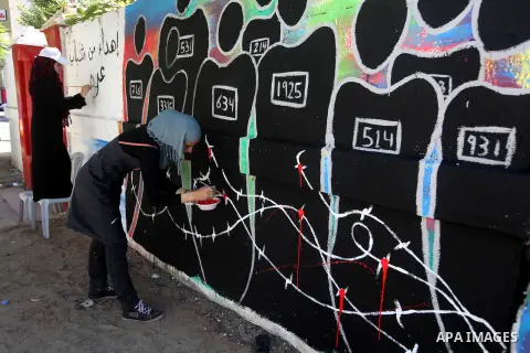 Palestinian artists draw a graffiti in front of the red cross office during a ceremony to support the prisoners in Israeli jails, in Gaza city on 26 September 2012. Photo by Majdi Fathi