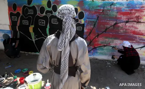 Palestinian artists draw a graffiti in front of the red cross office during a ceremony to support the prisoners in Israeli jails, in Gaza city on 26 September 2012. Photo by Majdi Fathi
