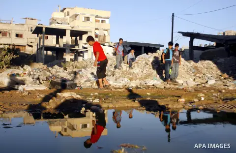 Palestinian children stand near an erupting sewage pipeline, in Rafah refugee camp southern the Gaza strip, Sept 26, 2012. In the aftermath of the Israeli military Operation Cast Lead in 2008/2009, Palestinian refugees i...