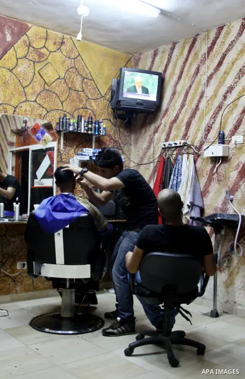 Palestinians watch TV during the speech of Palestinian President Mahmoud Abbas at the at UN headquarters in New York in the 67th session of the United Nations General Assembly, at a coiffure shop in the West Bank city of...