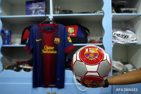 A Palestinian boy displays a football with the logo of Barcelona's soccer team at a sport store in Rafah in the southern Gaza strip, Sept. 27, 2012. Hamas is launching a media boycott of Barcelona after reports the Spani...