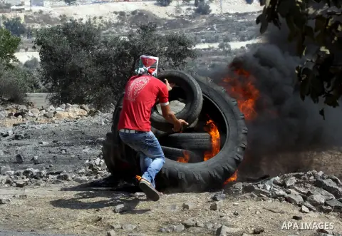 A Palestinian protester burns tires after a demonstration against the expropriation of Palestinian land by Israel in the village of Kfar Qaddum, near the West Bank city of Nablus, on september 28, 2012. Photo by Nedal Es...