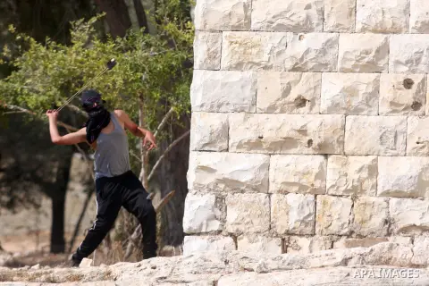 A Palestinian protester hurls stones at Israeli soldiers during a weekly protest against the expansion of the nearby Jewish settlement of Halamish, in the West Bank village of Nabi Saleh near Ramallah, Friday, Sept 28, 2...