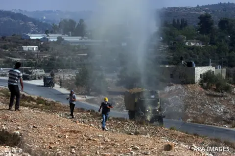 Palestinian protesters run away from a water canon used by Israeli troops to disperse protesters during a weekly protest against the expansion of the nearby Jewish settlement of Halamish, in the West Bank village of Nabi...