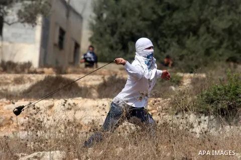 A Palestinian protester hurls stones at Israeli soldiers during a weekly protest against the expansion of the nearby Jewish settlement of Halamish, in the West Bank village of Nabi Saleh near Ramallah, Friday, Sept 28, 2...