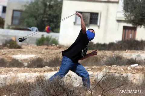 A Palestinian protester hurls stones at Israeli soldiers during a weekly protest against the expansion of the nearby Jewish settlement of Halamish, in the West Bank village of Nabi Saleh near Ramallah, Friday, Sept 28, 2...