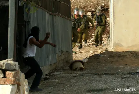 A Palestinian protester throw stones at Israeli troops after a demonstration against the expropriation of Palestinian land by Israel in the village of Kfar Qaddum, near the West Bank city of Nablus,Palestinian protesters...