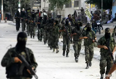 Palestinian militants from the Islamic Jihad, an armed wing of the Al-Quds Brigades hold weapons during a rally marking the 25th anniversary of the Jihad movement's establishment in Rafah in the southern Gaza Strip on Oc...