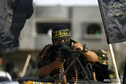 Palestinian militants from the Islamic Jihad, an armed wing of the Al-Quds Brigades hold weapons during a rally marking the 25th anniversary of the Jihad movement's establishment in Rafah in the southern Gaza Strip on Oc...