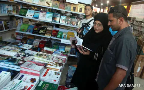 Palestinian visitors read books at a booth during the launch of the International Book Fair Exhibition, in Gaza city , Oct. 03, 2012. The Gaza International Book Fair has participated with more than 70 publishers from Pa...