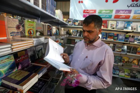 A Palestinian visitor reads a book at a booth during the launch of the International Book Fair Exhibition, in Gaza city , Oct. 03, 2012. The Gaza International Book Fair has participated with more than 70 publishers from...