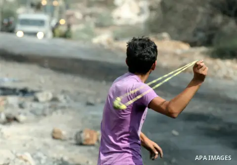 A Palestinian protester uses a sling shot to hurl stons at Israeli soldiers during clashes following a demonstration against the expropriation of Palestinian land by Israel in the village of Kafr Qadum in the occupied We...