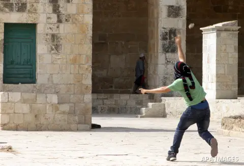 A Palestinian worshipper throws stones toward Israeli forces, not pictured, during clashes at the Al Aqsa Mosque compound, known by the Jews as the Temple Mount, in Jerusalem's Old City, Friday, Oct. 5, 2012. Earlier thi...