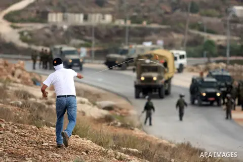 A Palestinian protester hurls stones at Israeli soldiers during a weekly protest against the expansion of the nearby Jewish settlement of Halamish, in the West Bank village of Nabi Saleh near Ramallah, Friday, Oct 5, 201...