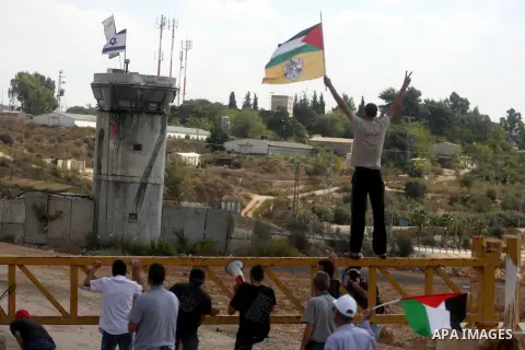 Palestinian demonstrators hold a national flags during a weekly protest against the expansion of the nearby Jewish settlement of Halamish, in the West Bank village of Nabi Saleh near Ramallah, Friday, Oct 5, 2012. Photo...