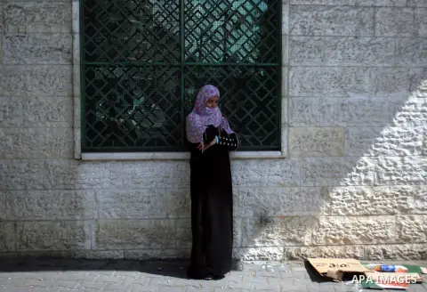 A Palestinian woman waits in front of a center for Social Affairs to receive the financial aid during the program of the Ministry of Social Affairs to help the people with special needs, in Rafah in southern Gaza strip,...
