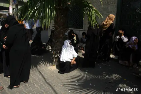 Palestinians wait in front of a center for Social Affairs to receive the financial aid during the program of the Ministry of Social Affairs to help the people with special needs, in Rafah in southern Gaza strip, Oct. 07,...