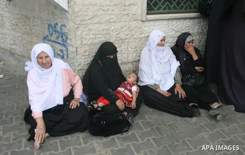 Palestinians wait in front of a center for Social Affairs to receive the financial aid during the program of the Ministry of Social Affairs to help the people with special needs, in Rafah in southern Gaza strip, Oct. 07,...