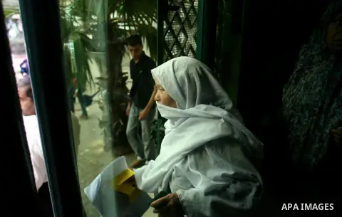 Palestinians wait in front of a center for Social Affairs to receive the financial aid during the program of the Ministry of Social Affairs to help the people with special needs, in Rafah in southern Gaza strip, Oct. 07,...