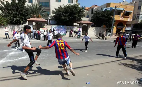 Palestinians with Barcelona's Lionel Messi's shirt and Real Madrid's Portuguese Cristiano Ronaldo's shirt play football in front of the Red Cross headquarter during sit-in to support Mahmud Sarsak, a Palestinian football...