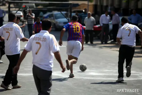 Palestinians with Barcelona's Lionel Messi's shirt and Real Madrid's Portuguese Cristiano Ronaldo's shirt play football in front of the Red Cross headquarter during sit-in to support Mahmud Sarsak, a Palestinian football...
