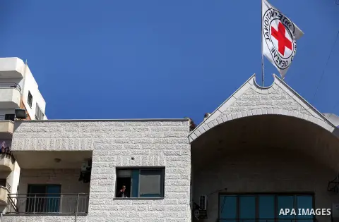 An employee in the Red Cross headquarter in Gaza looks at Palestinians with Barcelona's forward Lionel Messi's shirt and Real Madrid's Portuguese Cristiano Ronaldo's shirt as they play football during sit-in to support M...