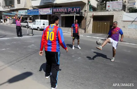 Palestinians with Barcelona's Lionel Messi's shirt and Real Madrid's Portuguese Cristiano Ronaldo's shirt play football in front of the Red Cross headquarter during sit-in to support Mahmud Sarsak, a Palestinian football...