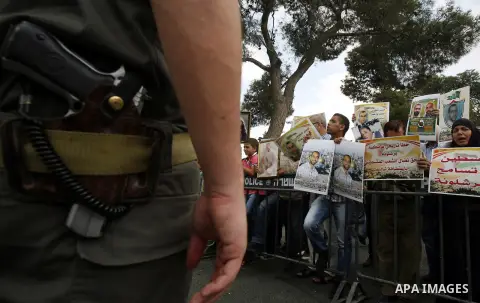 Families of Palestinian prisoners in Israeli jails hold their portraits and placards, bearing a portrait of Israeli soldier Gilad Shalit on the emblem of Spanish FC Barcelona football club, during a demonstration outside...