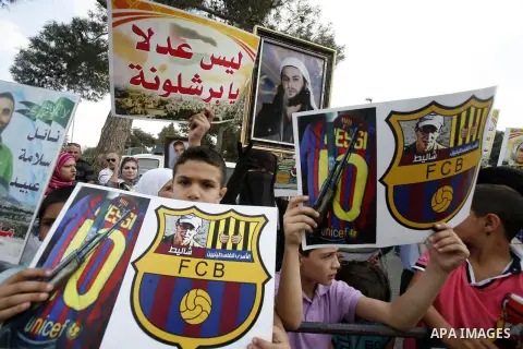 Families of Palestinian prisoners in Israeli jails hold their portraits and placards, bearing a portrait of Israeli soldier Gilad Shalit on the emblem of Spanish FC Barcelona football club, during a demonstration outside...