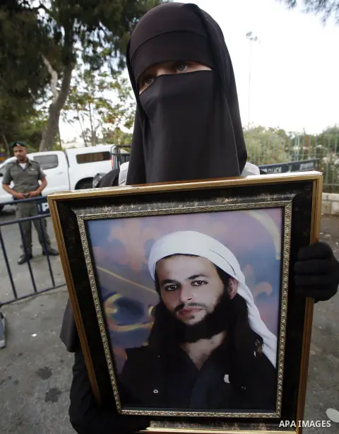 Families of Palestinian prisoners in Israeli jails hold their portraits and placards, bearing a portrait of Israeli soldier Gilad Shalit on the emblem of Spanish FC Barcelona football club, during a demonstration outside...