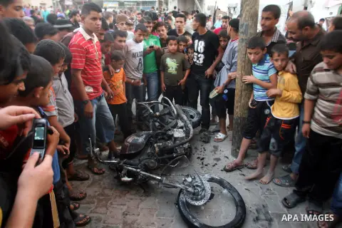Palestinians gather around a destroyed motorcycle following an Israeli air strike in Rafah camp in the southern Gaza Strip October 7, 2012. A missile fired by an Israeli aircraft hit and wounded two Palestinian militants...