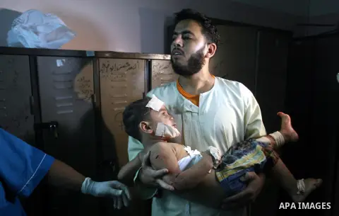 A Palestinian man carries his wounded child in a hospital following an Israeli air strike in Rafah camp in the southern Gaza Strip October 7, 2012. A missile fired by an Israeli aircraft hit and wounded two Palestinian m...