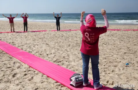 Palestinian youths stand on a beach in Gaza City near a pink ribbon as part of the Breast Cancer Awareness campaign on October 10, 2012. Photo by Majdi Fathi