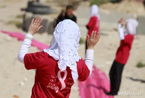 Palestinian youths stand on a beach in Gaza City near a pink ribbon as part of the Breast Cancer Awareness campaign on October 10, 2012. Photo by Majdi Fathi
