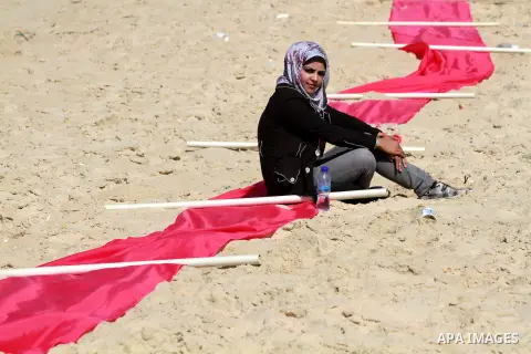 A Palestinian girl sits on a beach in Gaza City near a pink ribbon as part of the Breast Cancer Awareness campaign on October 10, 2012. Photo by Majdi Fathi