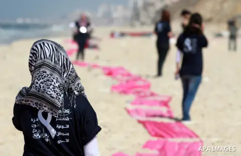 Palestinian youths stand on a beach in Gaza City near a pink ribbon as part of the Breast Cancer Awareness campaign on October 10, 2012. Photo by Majdi Fathi