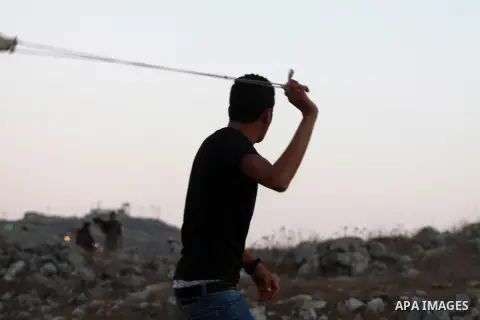 A Palestinian youth throws stones toward Jewish settlers during clashes on October 10, 2012. Over 100 olive trees belonging to Palestinians in a West Bank village have been found uprooted, its mayor said, blaming local J...