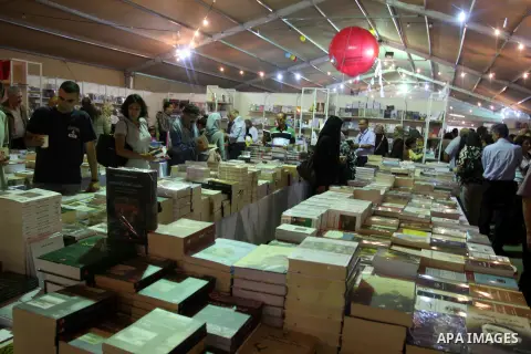 Palestinian visitors read books at a booth during the launch of the Palestine Book Fair Exhibition, in the West Bank city of Ramallah , Oct. 11, 2012. The Palestine 8th Book Fair has participated with more than 200 publi...