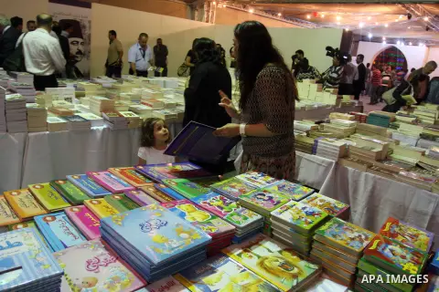 Palestinian visitors read books at a booth during the launch of the Palestine Book Fair Exhibition, in the West Bank city of Ramallah , Oct. 11, 2012. The Palestine 8th Book Fair has participated with more than 200 publi...