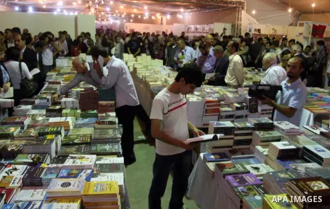Palestinian visitors read books at a booth during the launch of the Palestine Book Fair Exhibition, in the West Bank city of Ramallah , Oct. 11, 2012. The Palestine 8th Book Fair has participated with more than 200 publi...
