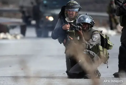 An Israeli soldier fires a tear gas canister at Palestinian protesters during clashes after a weekly protest against the expansion of the nearby Jewish settlement of Halamish, in the West Bank village of Nabi Saleh, near...