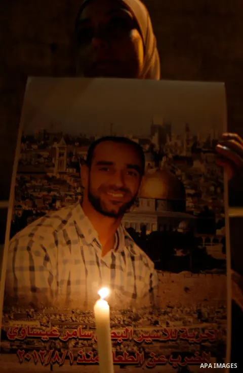 A Palestinian woman holds picture of prisoners and candles during a protest calling for the release of Palestinian prisoners from Israeli jails and in support of inmates on hunger strike, outside Damascus Gate in Jerusal...
