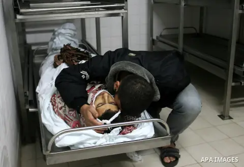 A Palestinian looks at the body of Yasser Al Attal in hospital morgue following an Israeli airstrike in area "Al fokhari" in east of Khan Younis in the southern Gaza Strip, on October 14, 2012. An Israeli air strike Satu...